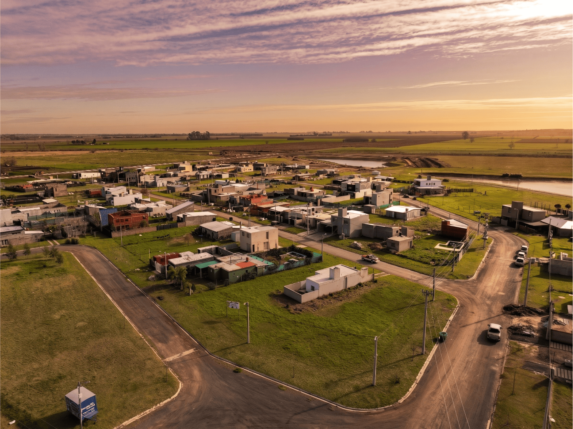 Vista aérea de un loteo residencial al atardecer, rodeado de naturaleza
