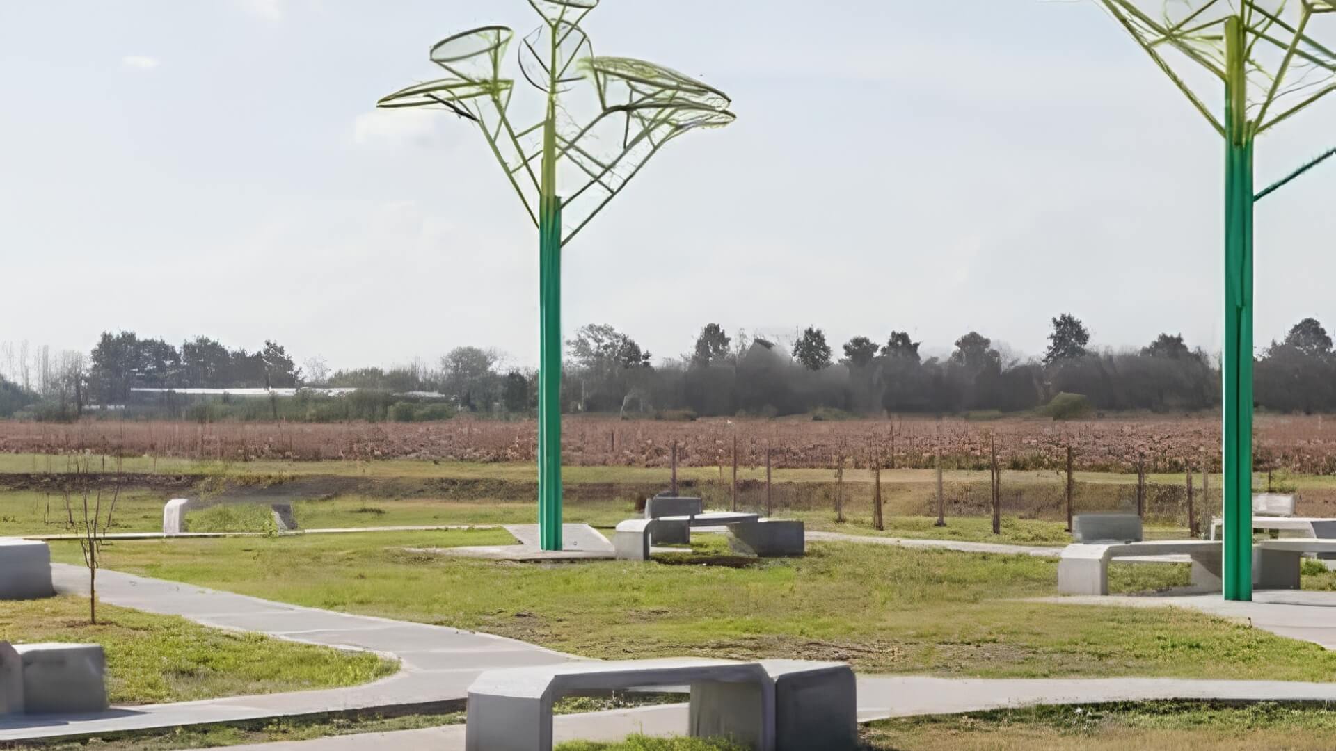 Parque con esculturas verdes en forma de árbol y bancos de hormigón entre campos